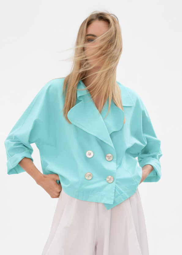 Woman wearing a light blue jacket with white buttons on a white background