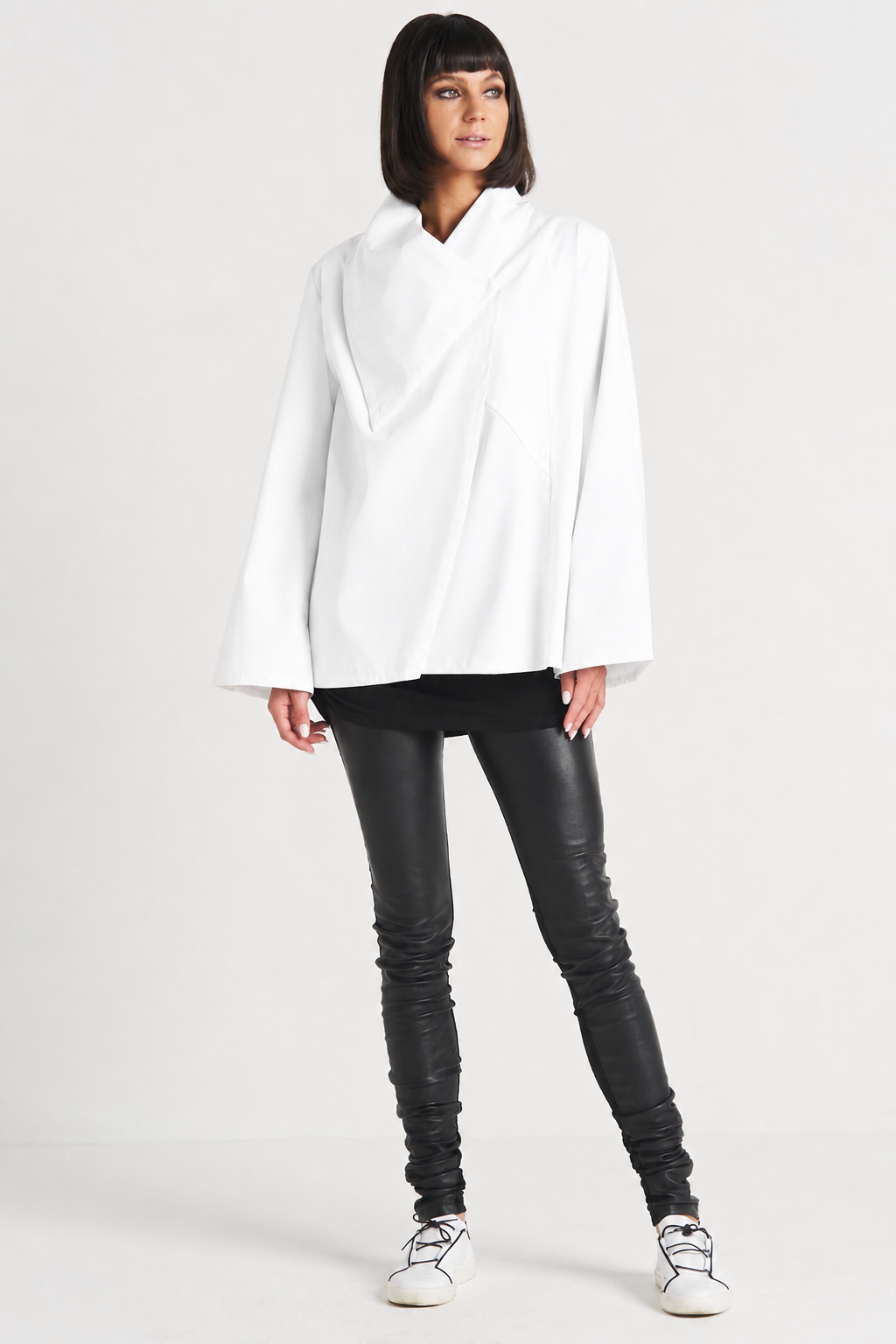 Woman wearing a white blouse and black leather pants on a white background