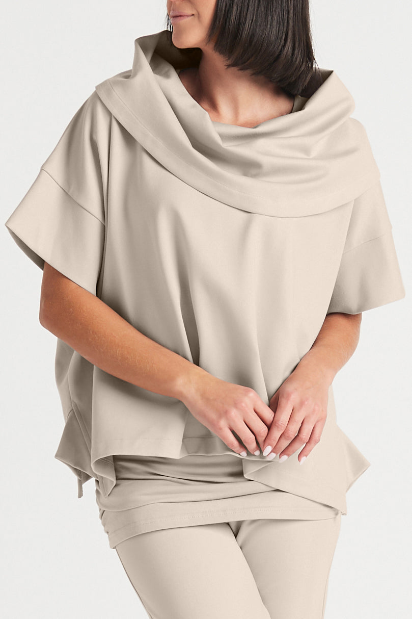 Woman wearing a beige draped top and pants on a white background
