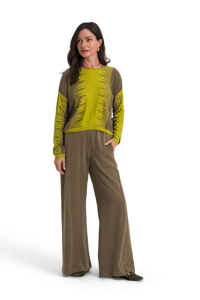 A woman modeling a two-piece outfit consisting of a lime green and brown patterned long-sleeve pima cotton top and matching brown wide-leg pants, shot against a solid white background.