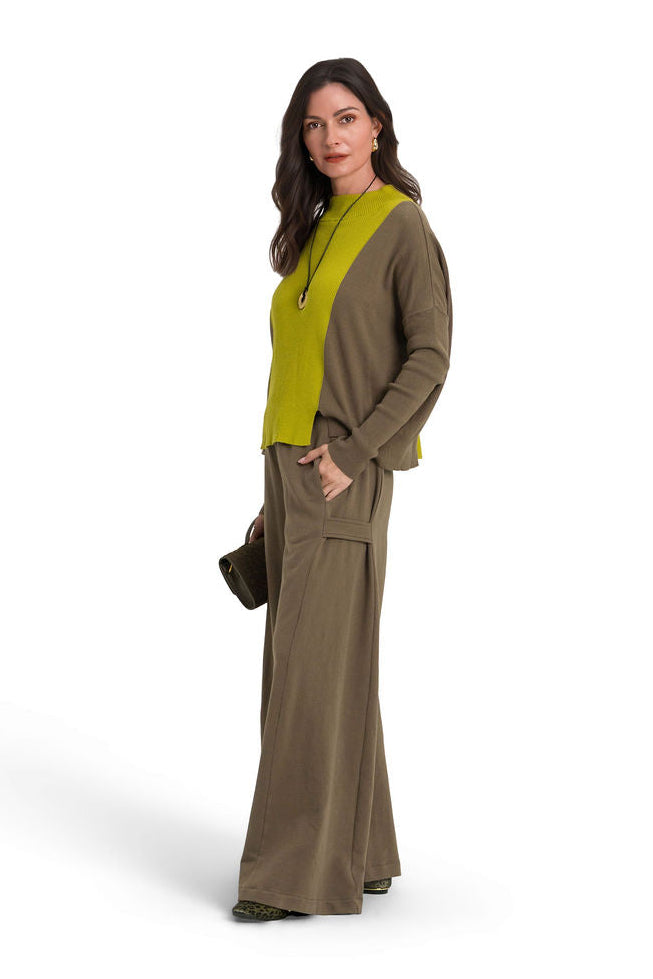 A woman modeling a two-piece olive green outfit consisting of a long-sleeve pima cotton sweater and matching 100% cotton french terry wide-leg pants, paired with a bright yellow-green knit vest, against a solid white background.