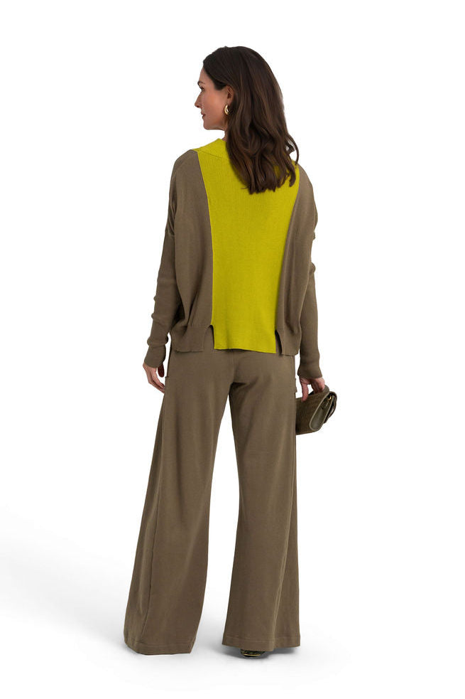 A woman is shown from behind wearing a matching olive green 100% cotton french terry wide-leg pants suit with a long-sleeve pima cotton sweater, holding a small dark green handbag against a solid white background.