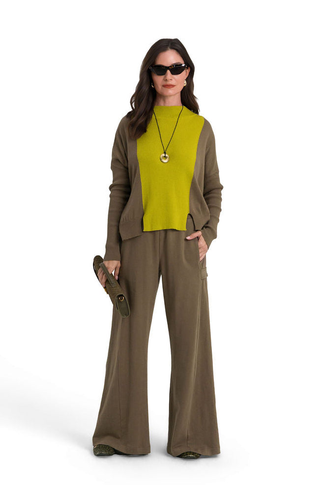 A female model stands against a white studio background wearing a matching olive-brown 100% cotton french terry wide-leg pants and pima cotton sweater set with a pea green knit top, sunglasses, and a long necklace.