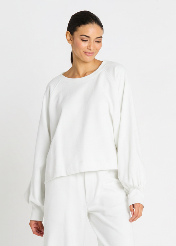 Woman wearing a white outfit against a light gray background