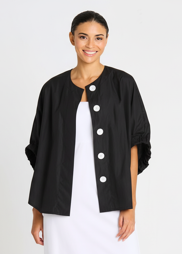 Woman wearing a black jacket with white buttons on a plain background