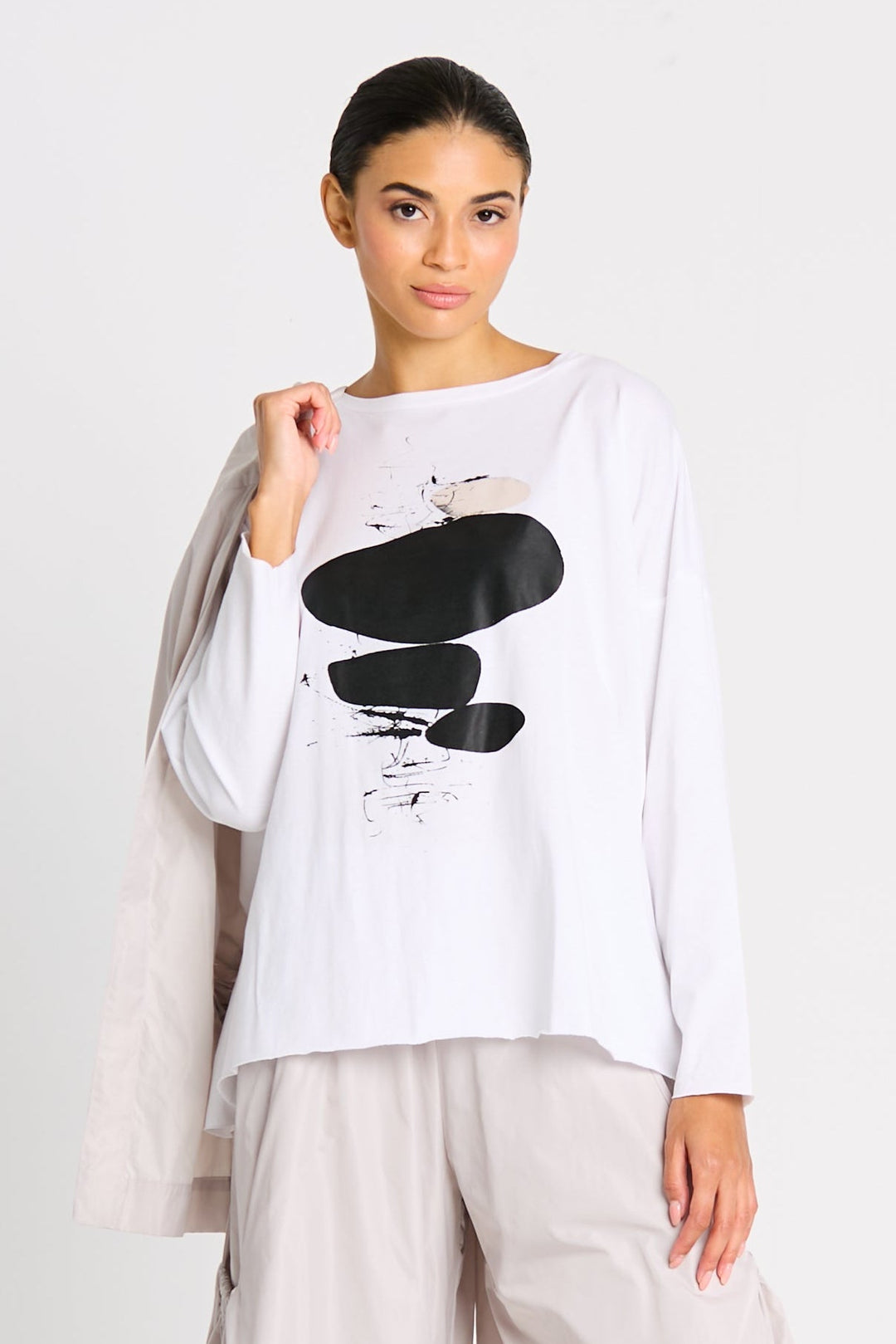Woman wearing a white long-sleeve pima cotton top with black abstract design on a plain background