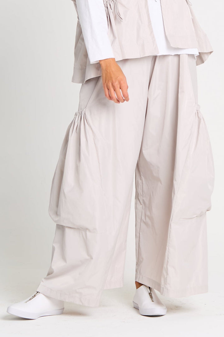 Light gray big pocket pants worn with a matching top on a white background