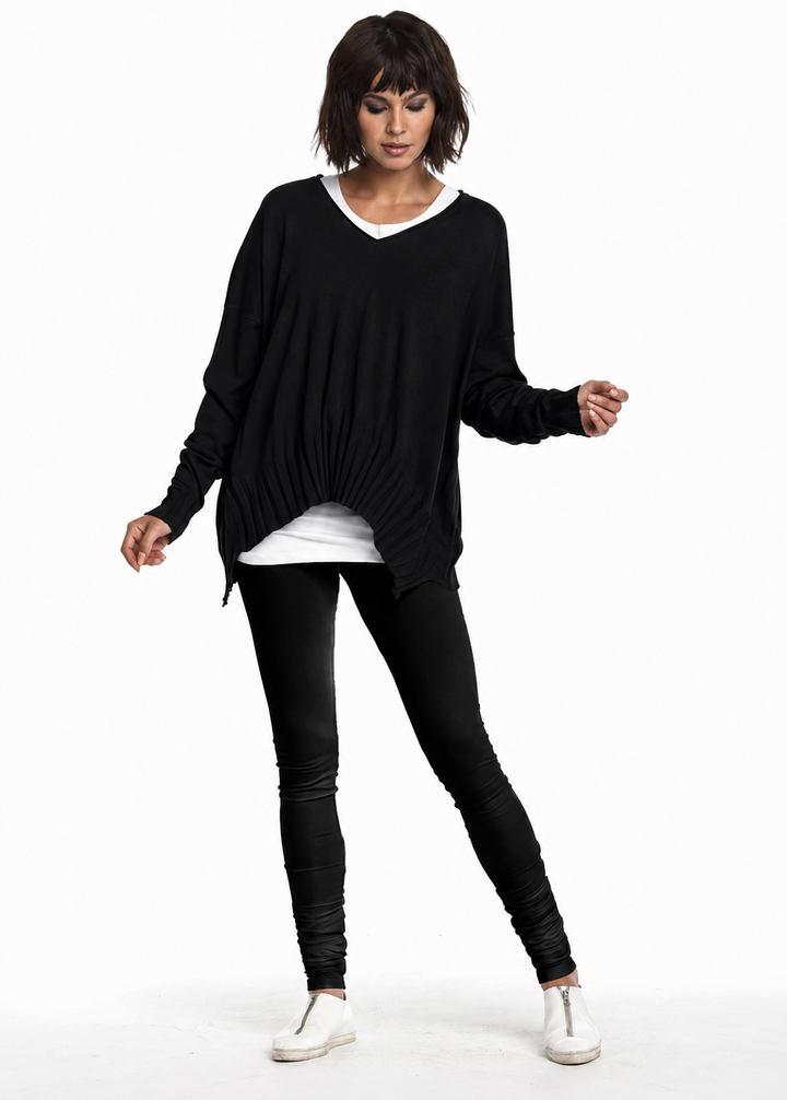 Woman wearing a black oversized sweater, white shirt, black leggings, and white sneakers on a white background