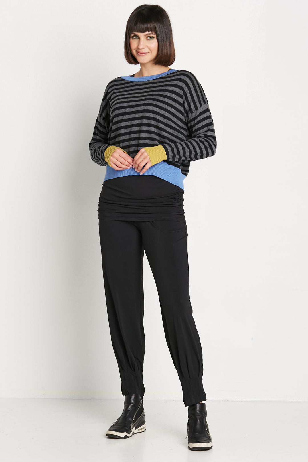 Woman wearing a pima cotton striped sweater and black pants on a white background