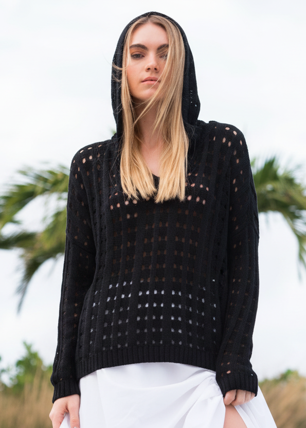 Woman wearing a light beige crochet sweater against a blurred natural background