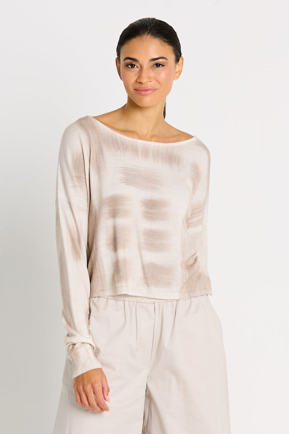 Woman wearing a beige tie-dye long-sleeve top and pants on a white background