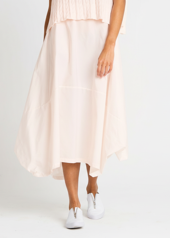 Person wearing a light pink blush skirt and white sneakers on a plain background