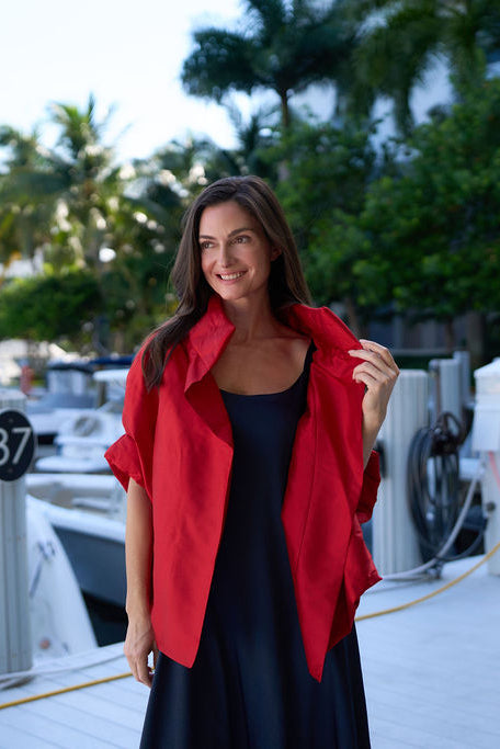 Woman in a red dupioni silk jacket standing on a dock with boats in the background
