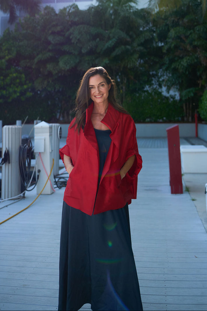 Woman in a dupioni silk jacket standing on a rooftop with palm trees and buildings in the background