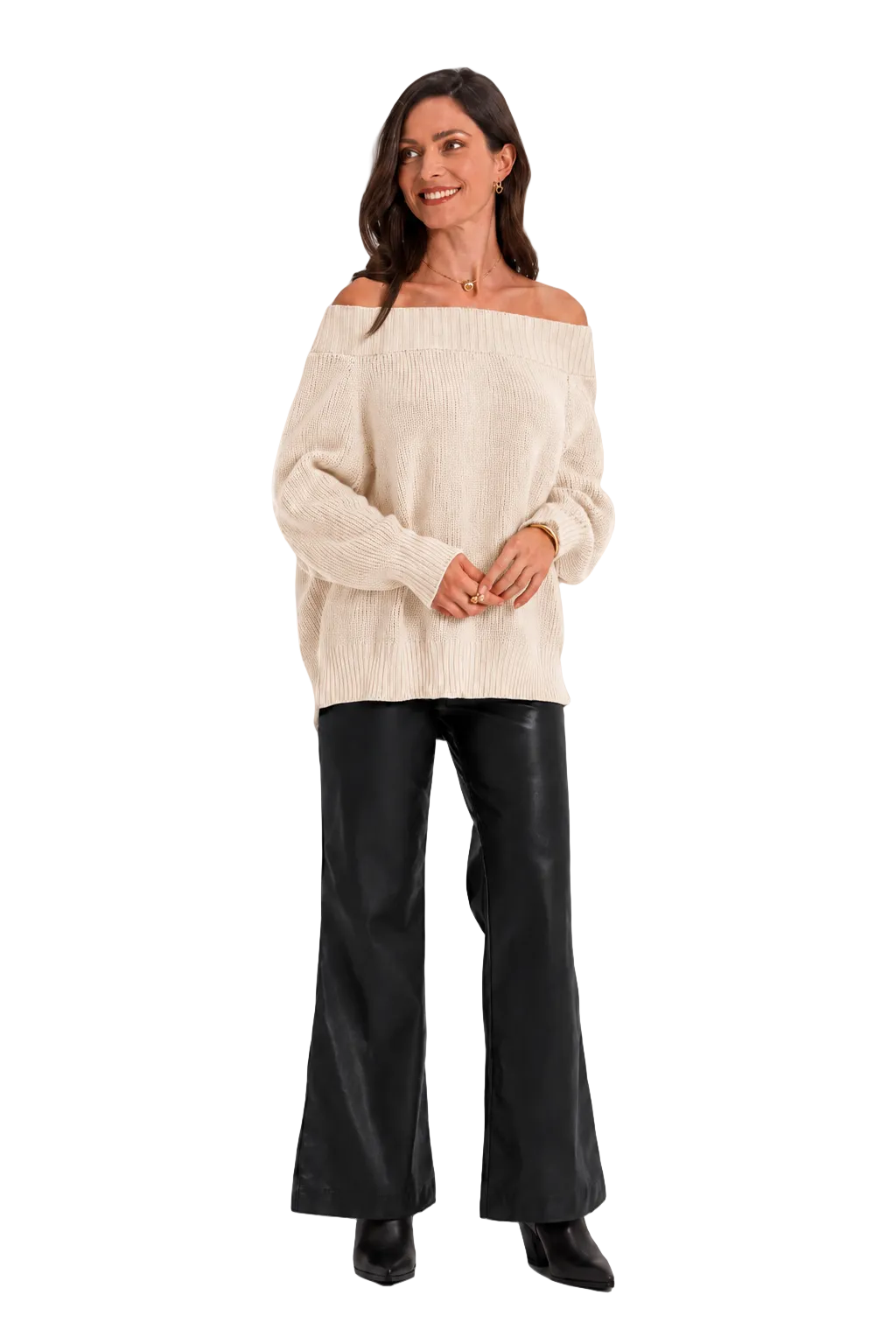 A woman modeling an off-the-shoulder cream knit sweater paired with black wide-leg pants and black boots, standing against a solid light gray studio background.