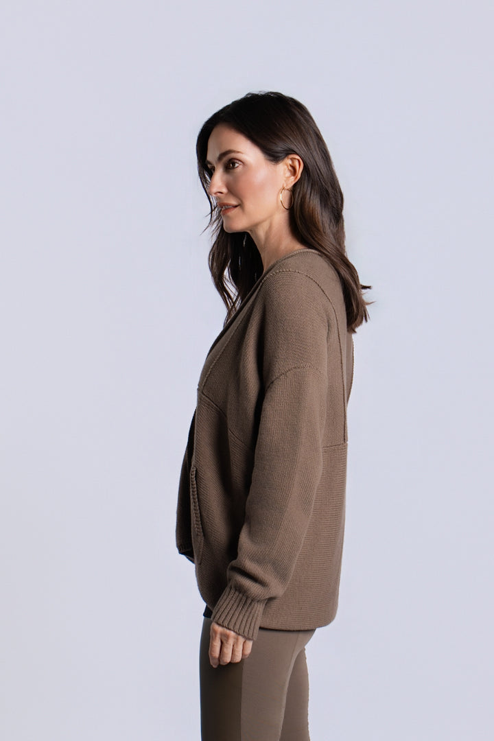 A woman shown in side profile wearing a taupe-brown knit pima cotton cardigan and matching knit pants against a light gray studio background.