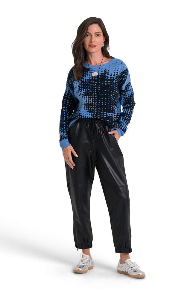 A woman modeling a long-sleeve knit pima cotton top with a blue-to-black gradient and black textured pants, standing against a plain white studio background.