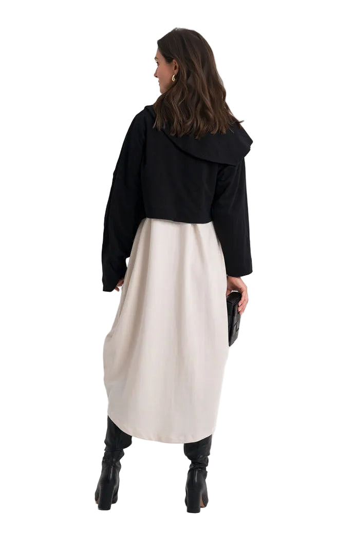 A woman is shown from behind wearing a 100% cotton black cropped long-sleeve top with a wide collar and a light beige midi skirt, paired with black ankle boots, against a plain white studio background.