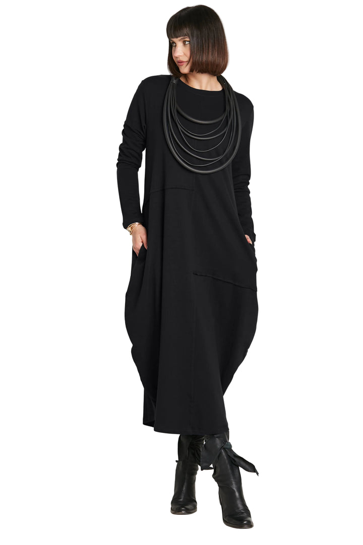 Woman wearing a 100% cotton long black dress with layered necklaces on a white background