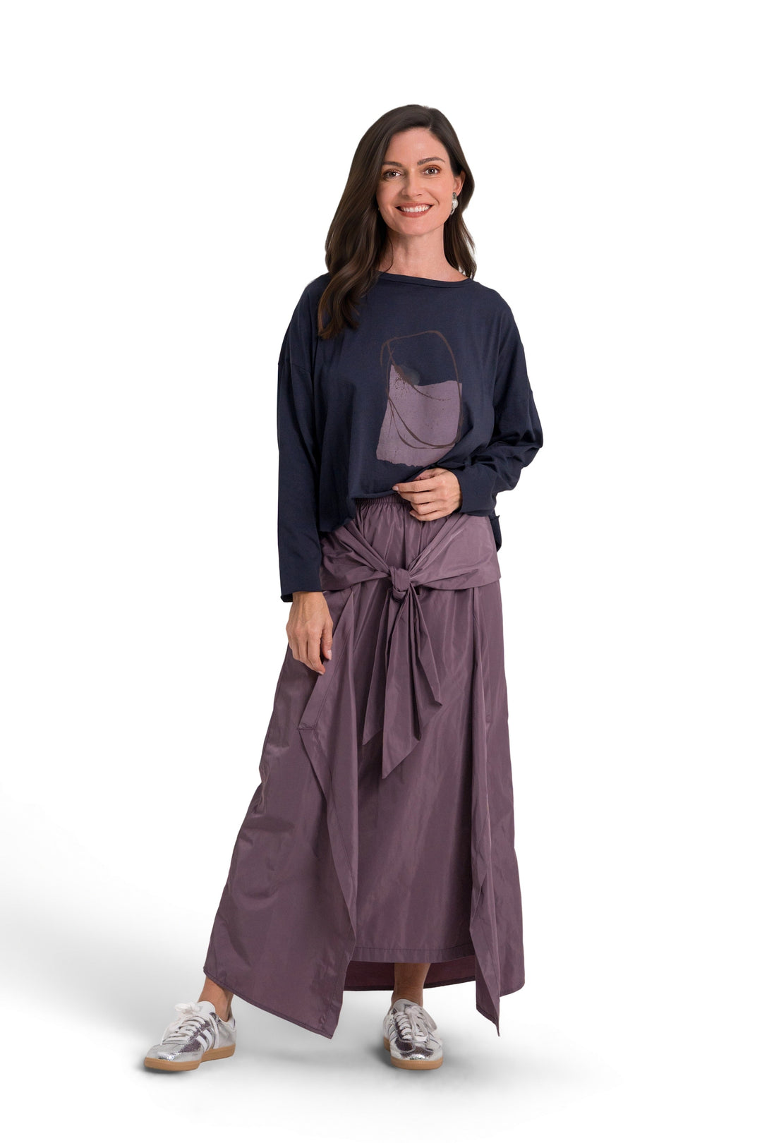 A woman modeling a 100% pima cotton dark navy blue long-sleeve top and a dusty purple wrap skirt with a matching belt, standing against a plain white background.