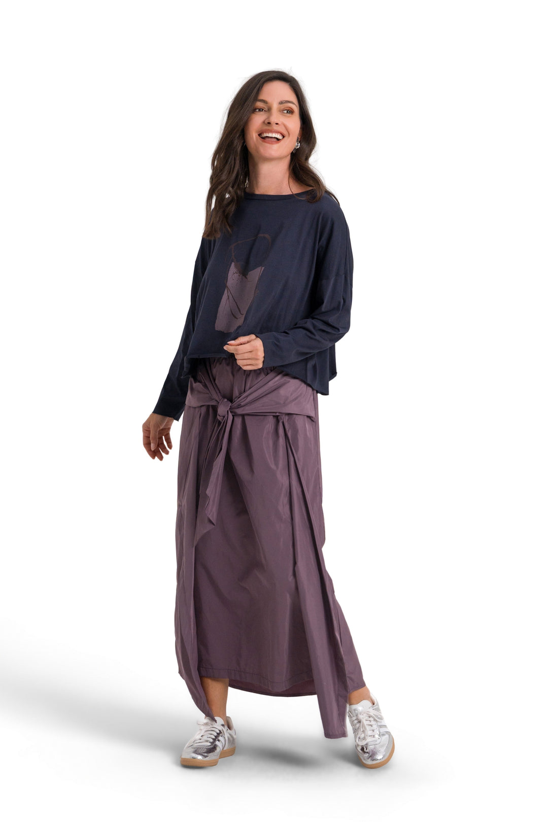 A woman modeling a 100% pima cotton dark navy blue long-sleeve top and a dusty purple wrap skirt, standing against a solid white background.