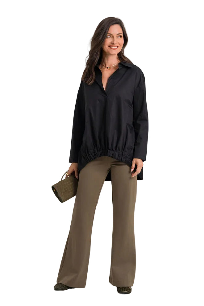 A woman modeling a 100% cotton black long-sleeve button-up shirt and olive green wide-leg pants, holding a matching olive green clutch bag against a solid white background.