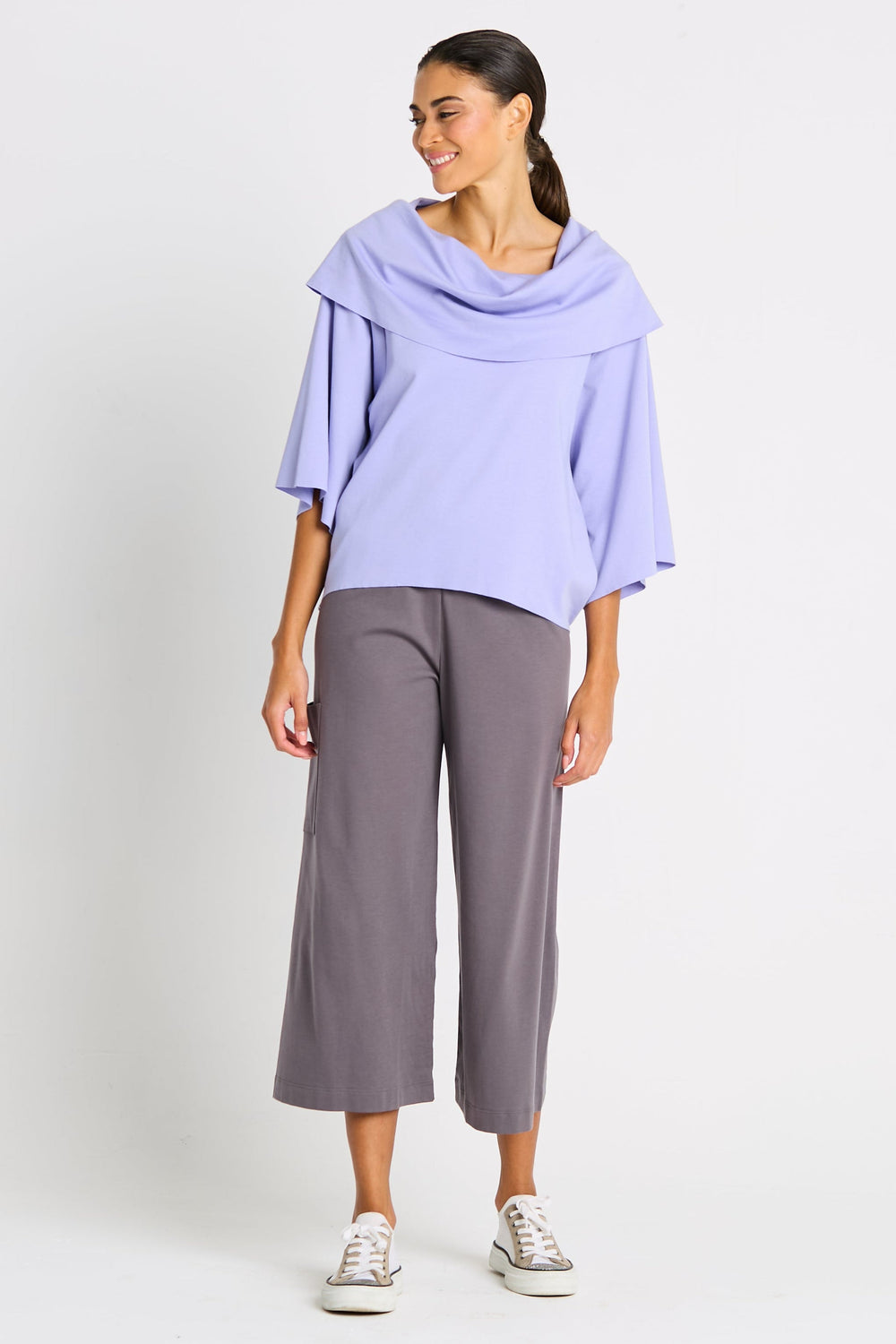 Woman wearing a light purple pima cotton top and gray pants on a white background