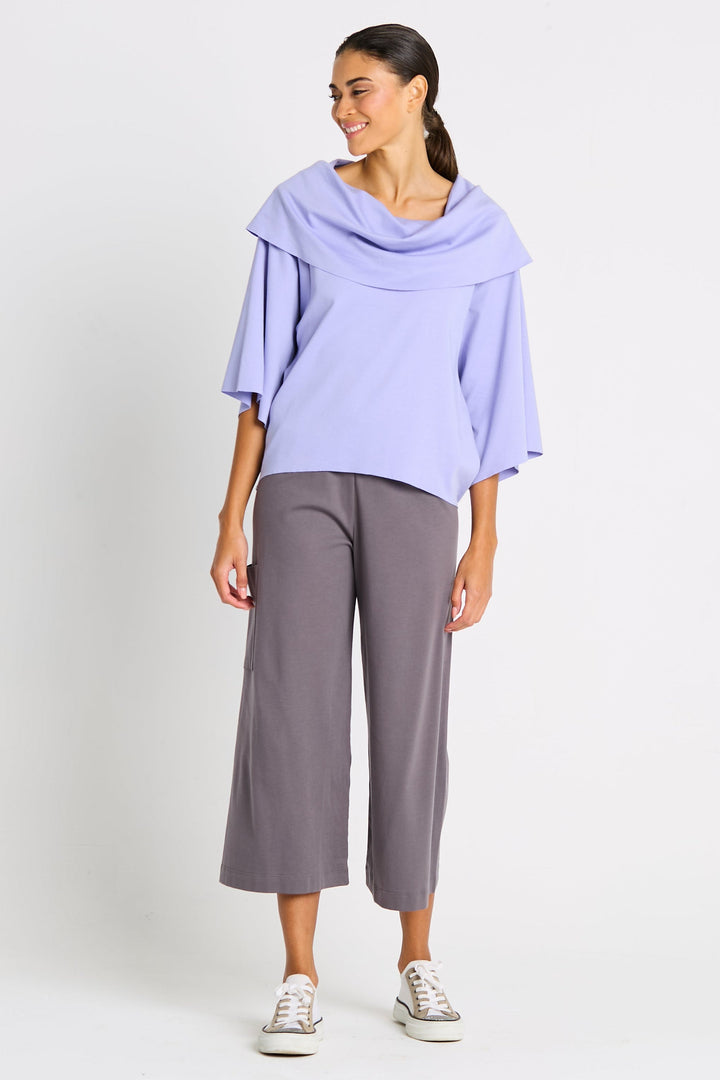 Woman wearing a light purple pima cotton top and gray pants on a white background