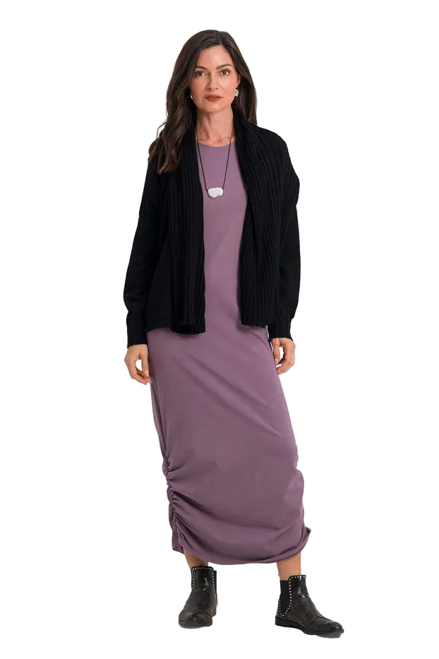 A woman modeling a long-sleeve mauve midi dress with a black ribbed cardigan, a silver pendant necklace, and black ankle boots, shot against a plain white studio background.