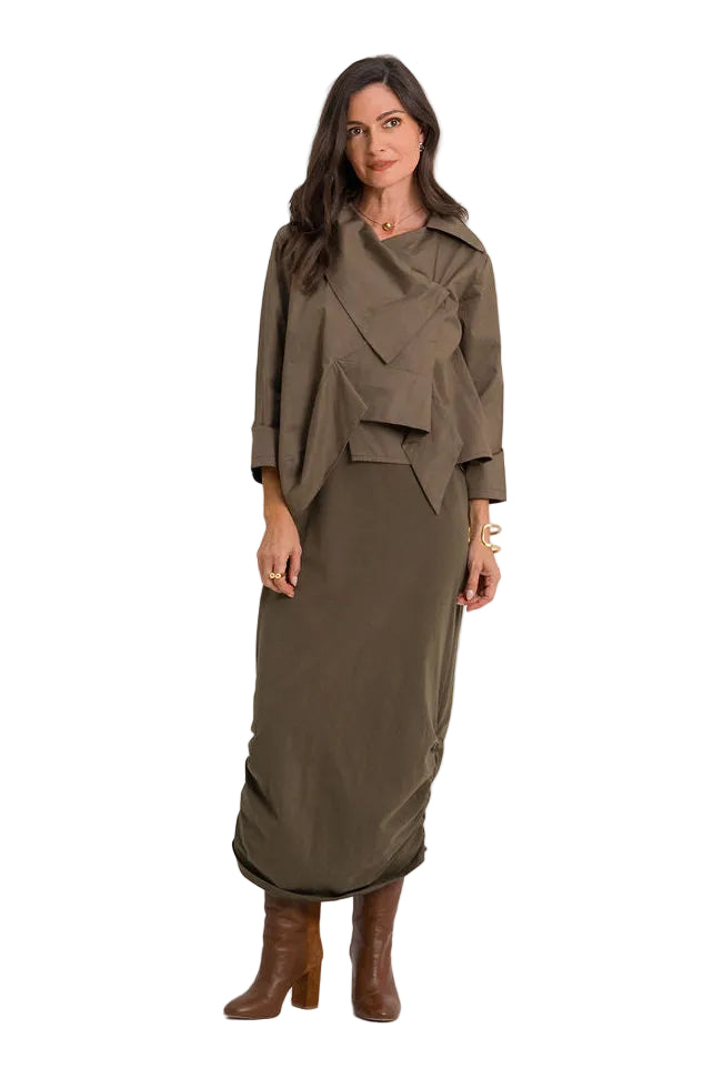 A woman modeling a 100% cotton long-sleeved, draped midi dress in olive brown, styled with brown leather ankle boots against a plain white studio background.