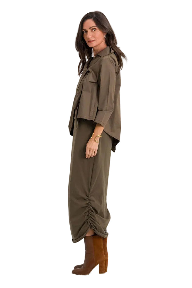 A woman modeling a matching two-piece outfit consisting of an 100% cotton olive green draped long-sleeve top and matching gathered wide-leg trousers, paired with brown ankle boots, against a plain white studio background.