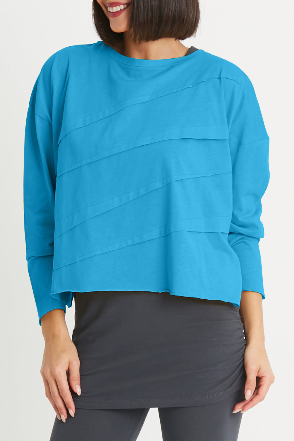 Woman wearing a blue top and gray skirt on a white background