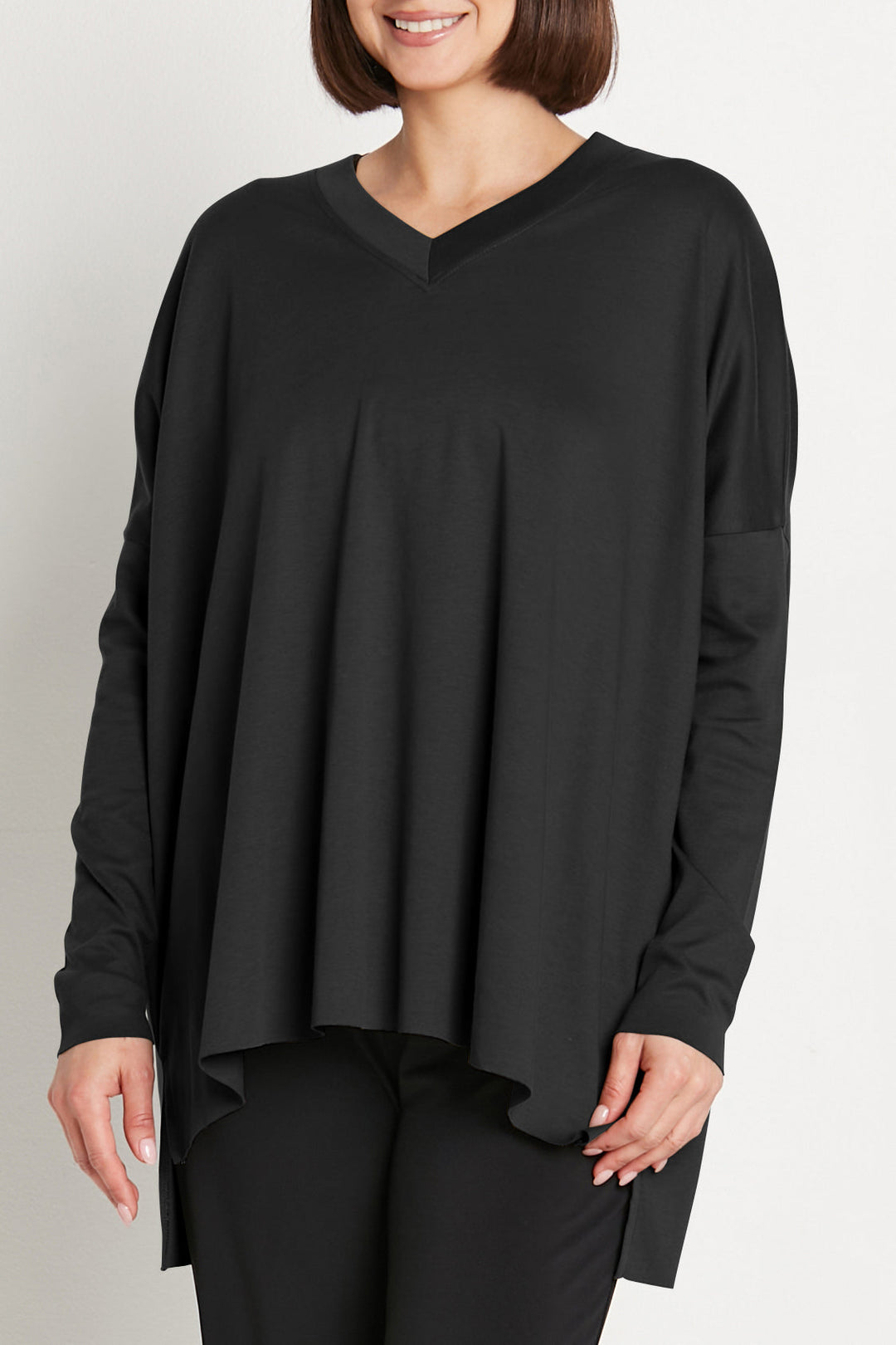 Woman wearing a black long-sleeve top against a plain background