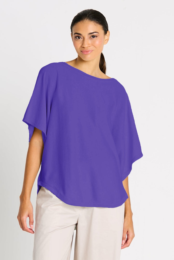 Woman wearing a purple blouse and beige pants on a white background