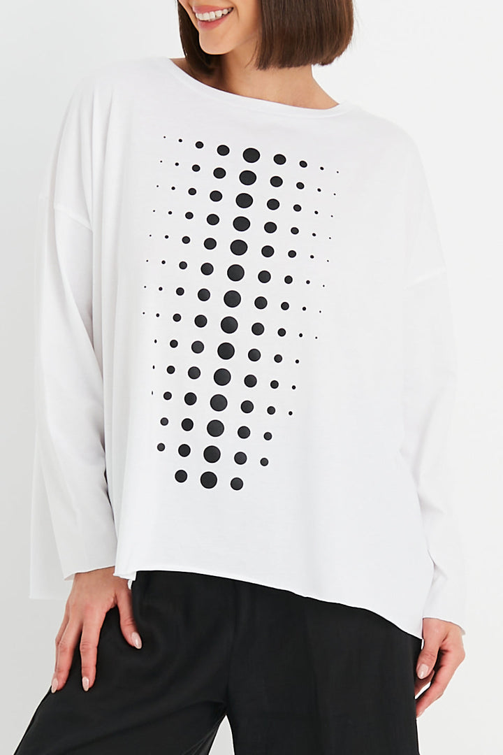 Woman wearing a pima cotton white shirt with black dot pattern on a plain background