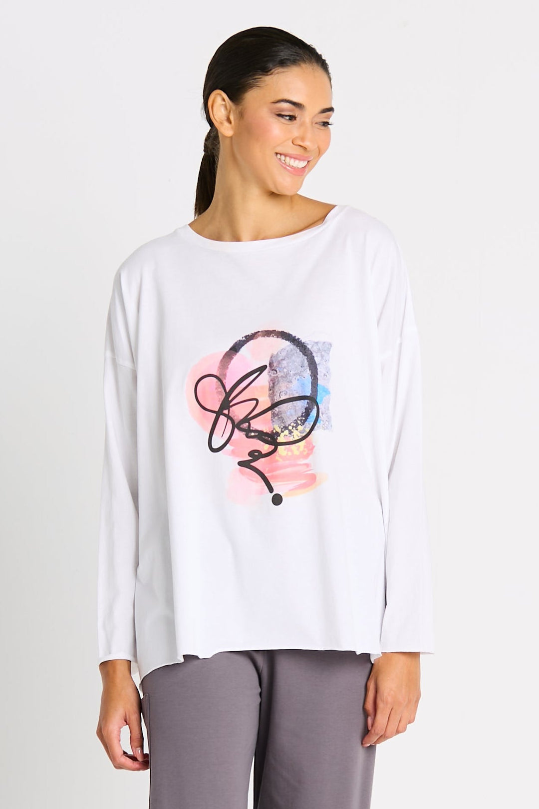 Woman wearing a luxury Pima cotton white long-sleeve shirt with a colorful graphic design on a plain background