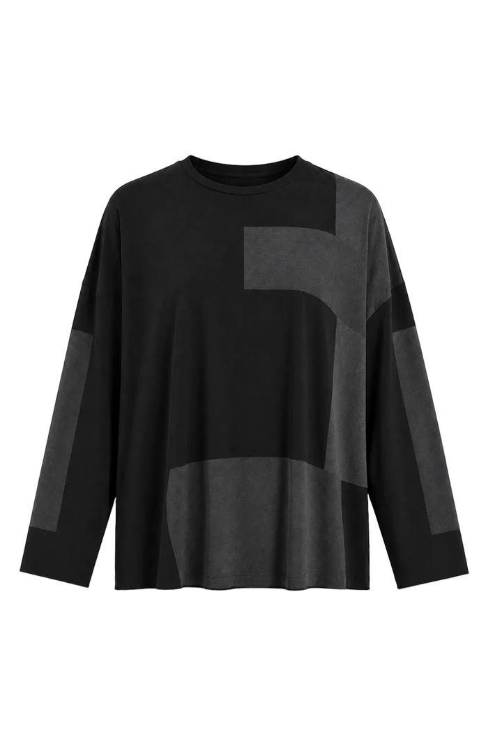 A 100% pima cotton black long-sleeve top with contrasting dark gray geometric color-block panels on the front and sleeves, displayed against a solid white background.