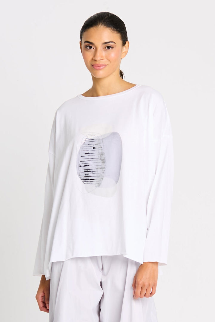 Woman wearing a luxury pima cotton white long-sleeve top with a graphic design on a plain background