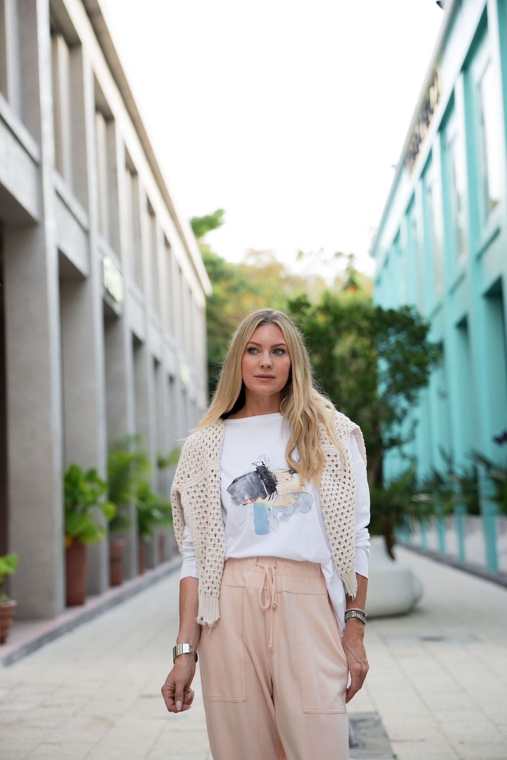 Woman standing outdoors in front of a building with a blurred background wearing a white pima cotton shirt.