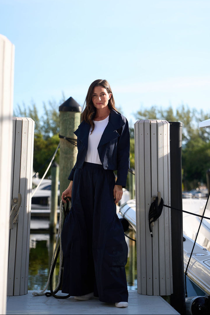 Woman standing on a dock with boats in the background wearing Planet big pocket pants in midnight blue.