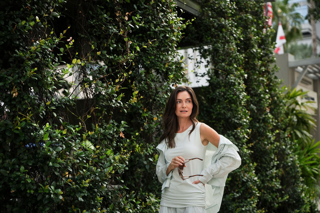 Woman in a mint outfit standing among green foliage