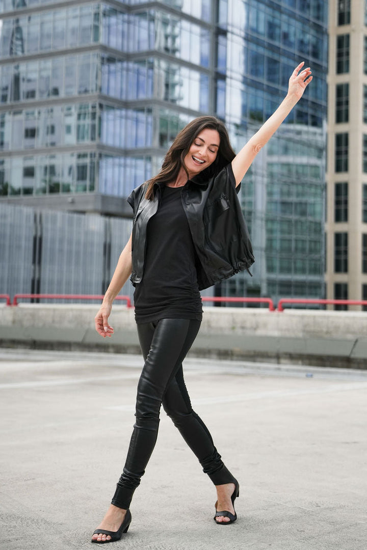 Woman in black outfit posing on a rooftop with modern buildings in the background