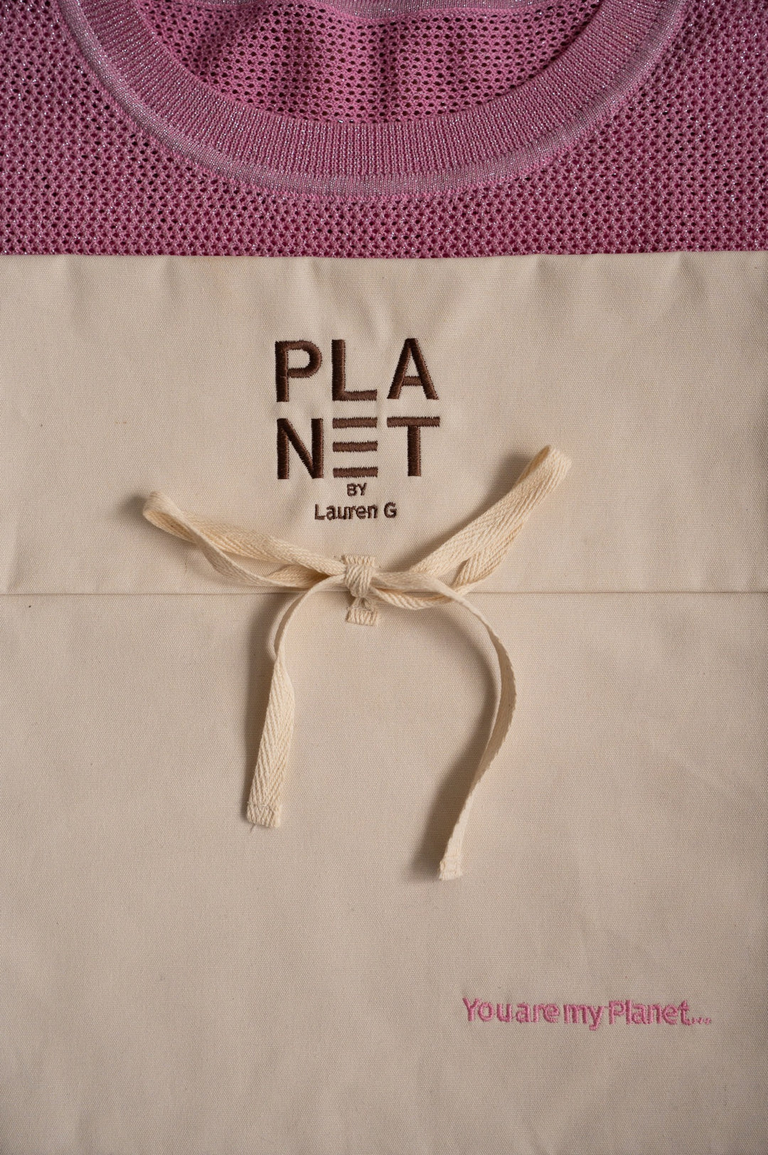 Beige mother's day tote bag with 'PLANET by Lauren G' text and pink sweater in the background